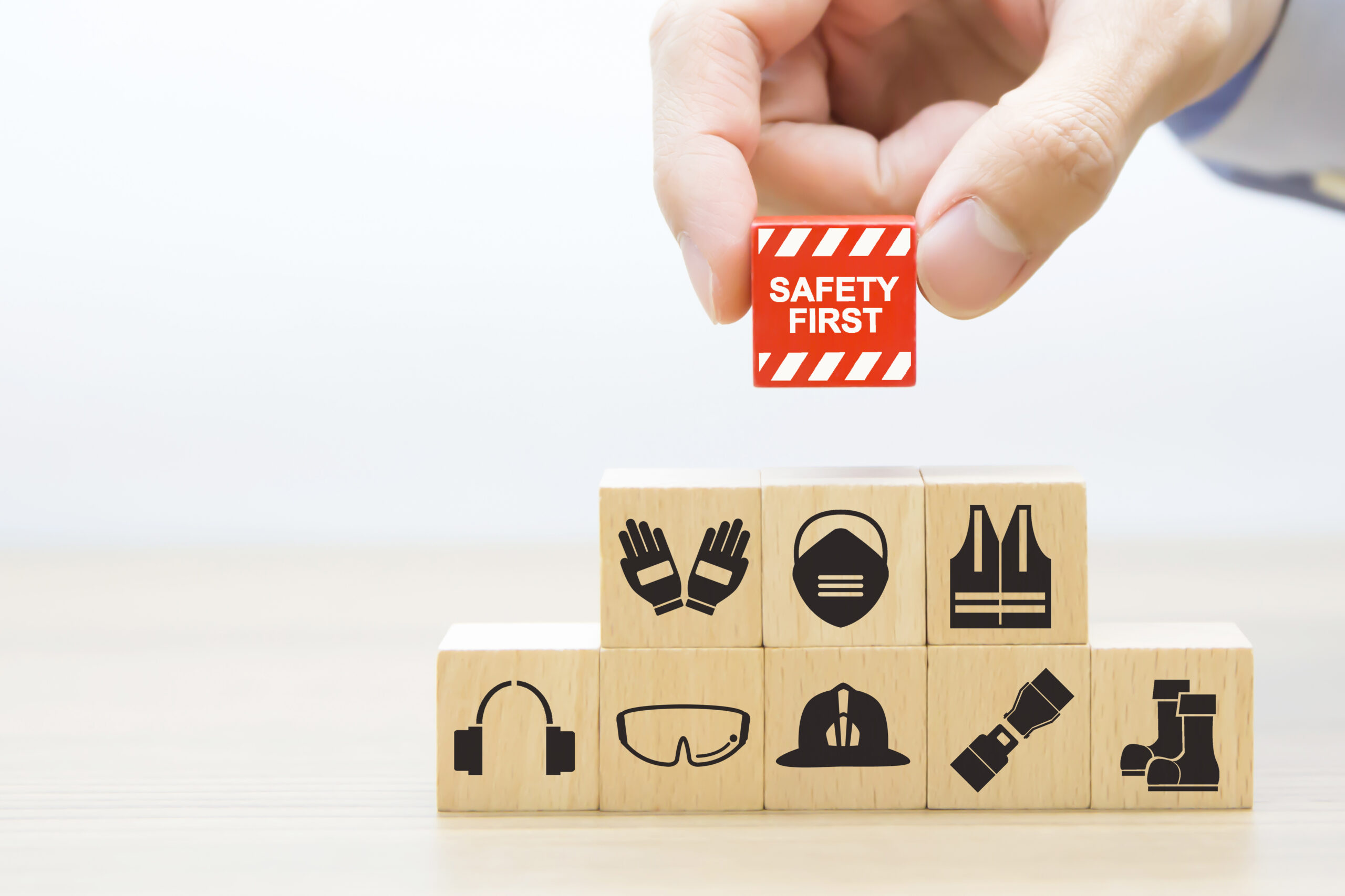 Close-up hand choose wooden blocks stacked with safety first icons.